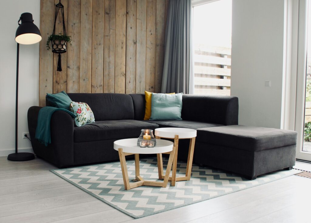 small room with grey corner sofa and wooden wall