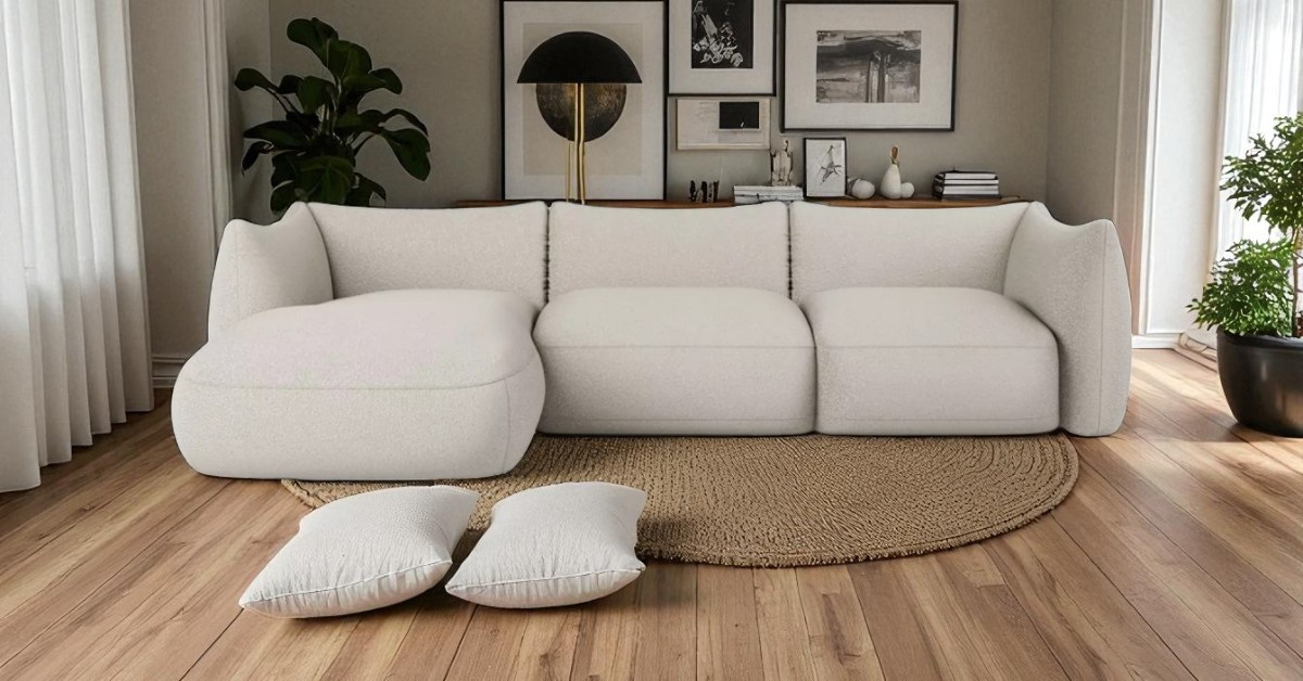 Modern living room with a cream corner sofa, round woven rug, wooden floor, decorative cushions, indoor plants and wall art creating a calm and elegant atmosphere.
