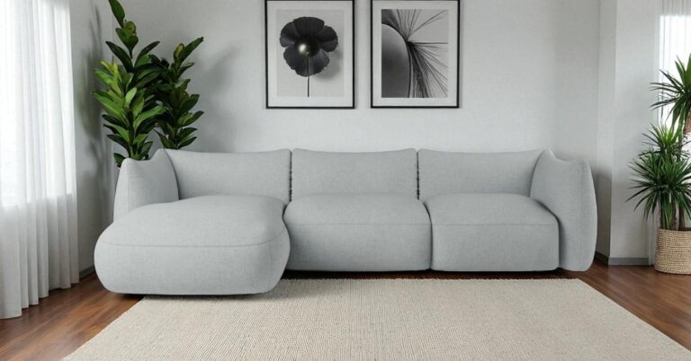 Bright modern living room with a light grey corner sofa, neutral rug, wooden floor, indoor plants and minimalist black-and-white wall art creating a calm contemporary interior.
