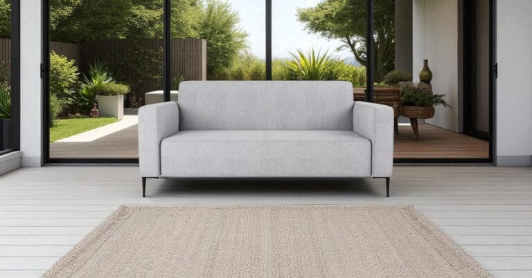 Best furniture ideas for an indoor-outdoor living space: Bolder grey sofa placed in an indoor-outdoor living space with open sliding doors, wooden deck, and garden view, creating a seamless indoor outdoor transition.