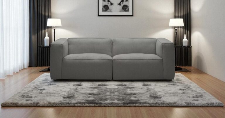Moved Modern grey sofa styled in a symmetrical living room with matching lamps, artwork and rug – symmetry in interior design inspiration.