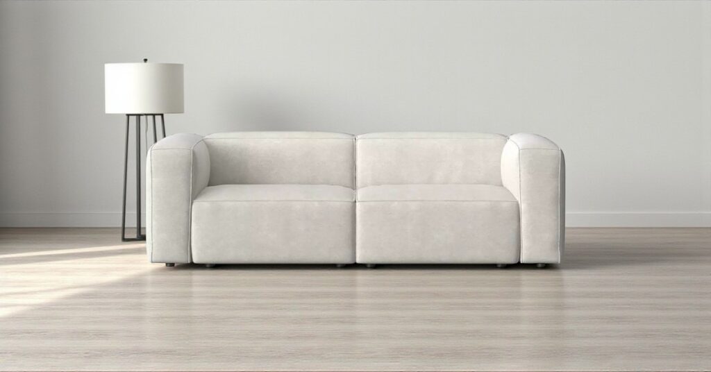Modern minimalist living room with a light grey modular sofa placed on wooden flooring against a neutral wall, styled with a tall floor lamp for balance.